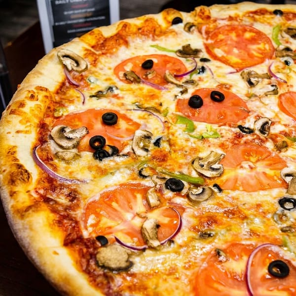 Freshly baked pizza with tomatoes, mushrooms, black olives, and red onions, from Carters Pizza.