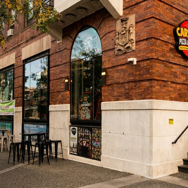 Urban street corner with Carters Pizza and Beer, Paris Baguette, and outdoor cafe seating.